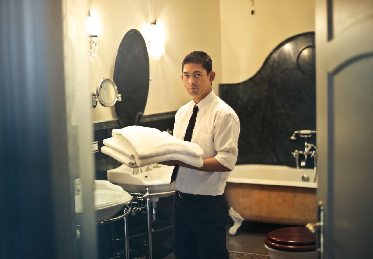 project-02-a A hotel employee holding towels in a luxury bathroom with elegant decor.